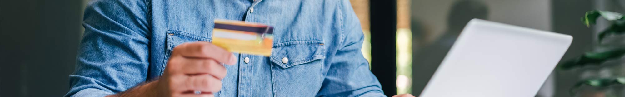 a man holding a debit card in front of a laptop