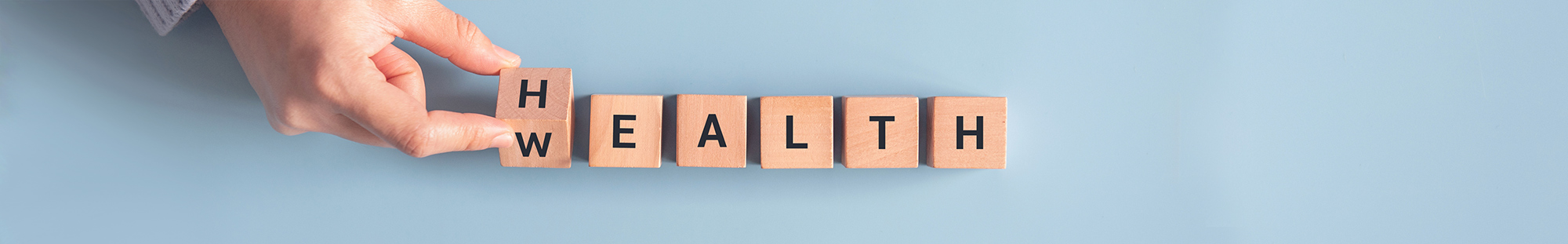 hand changing a letter block to spell wealth or health